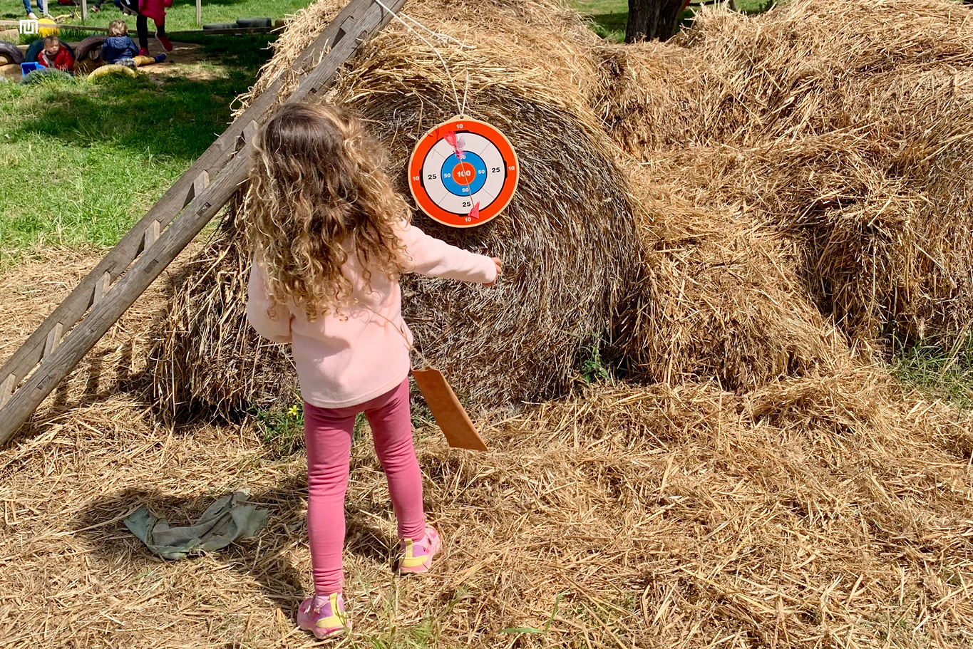 Bambina durante il Mitolab Artemide al Rifugio nel Bosco Siracusa mentre scocca una freccia con l’arco in un’attività educativa all’aperto
